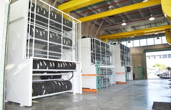 Three tire carousel racks storing tires in a warehouse setting.